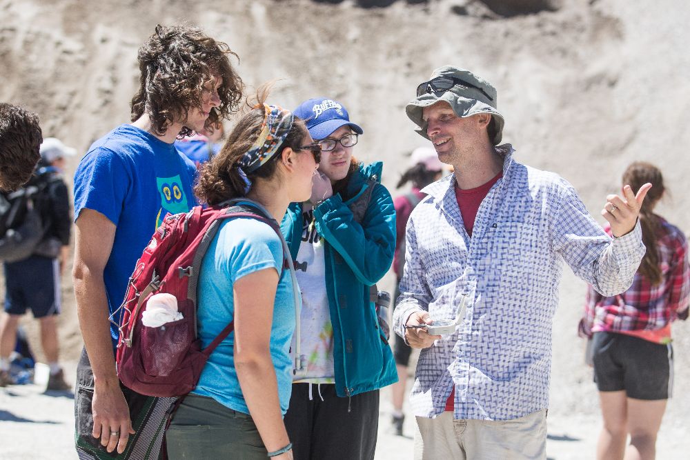 A professor chatting with a group of students.