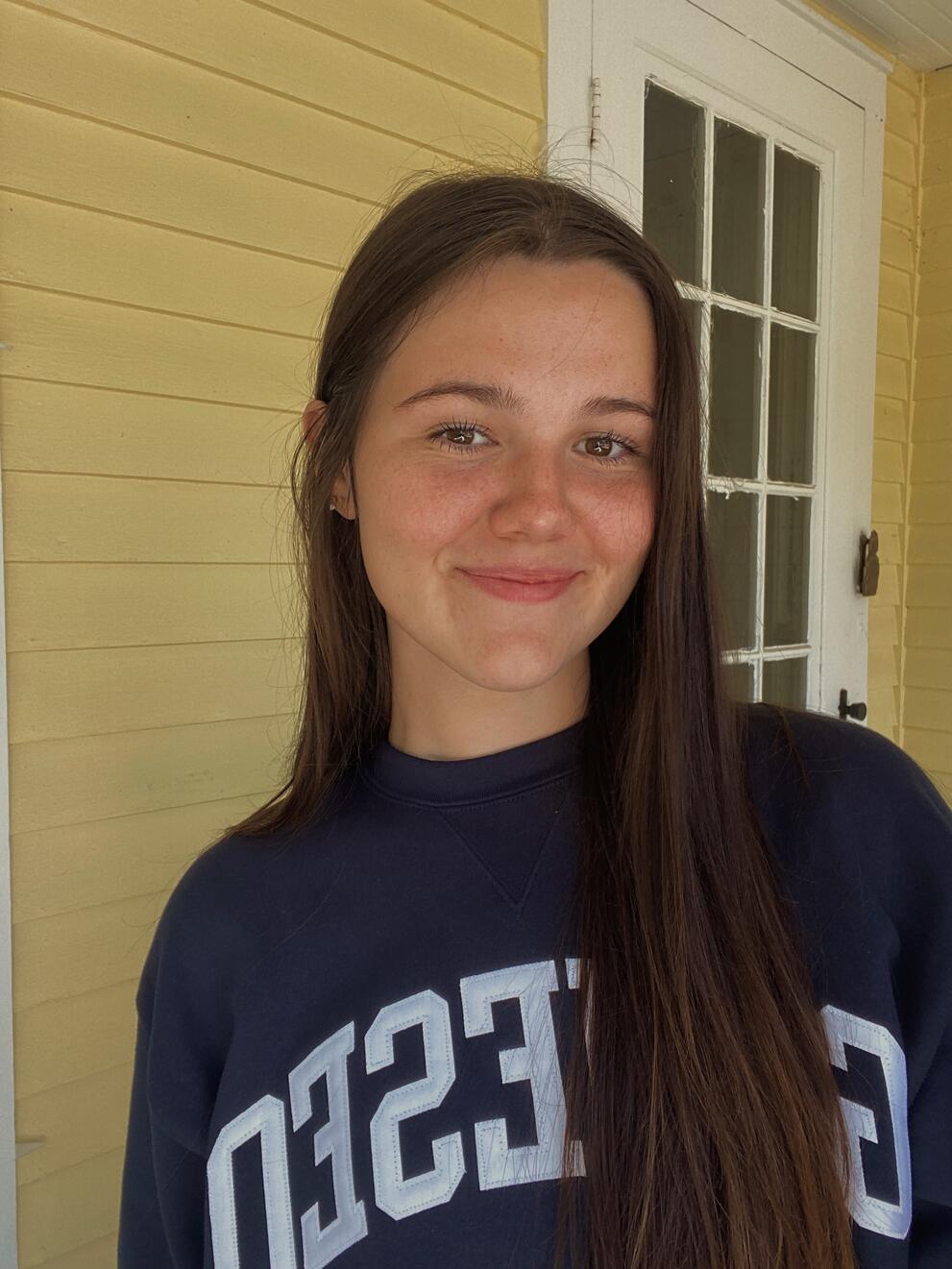 White woman with long brown hair wearing a Geneseo sweatshirt