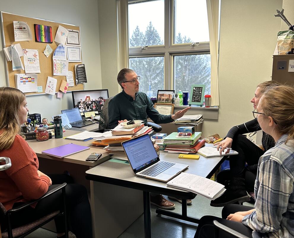 A professor answers student questions in an office