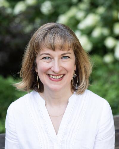 Alice Rutkowski sits on a bench outside in a white shirt