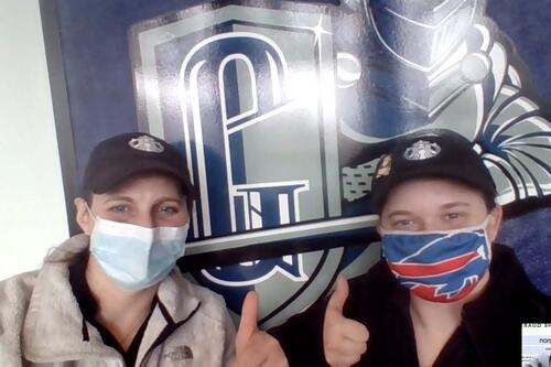 Manager Lindsay Cannon (left) standing in front of Geneseo shield with Brittany Taylor.