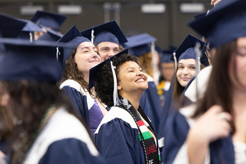 Female graduates look up and smile before the ceremony.