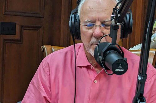 Portrait of George Speedy speaking into a microphone