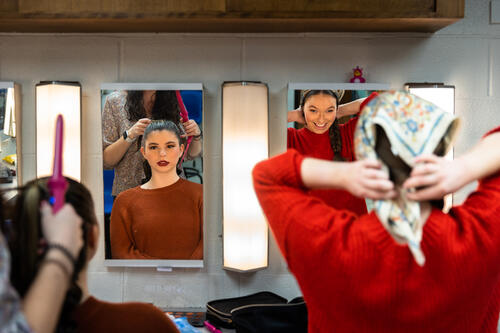 Alexis Blatz ’26, left, who played Alicia, a white Hollywood actress hired to portray a Native American, makes final costume and makeup preparations beside actress Hannarose Manning ’23.