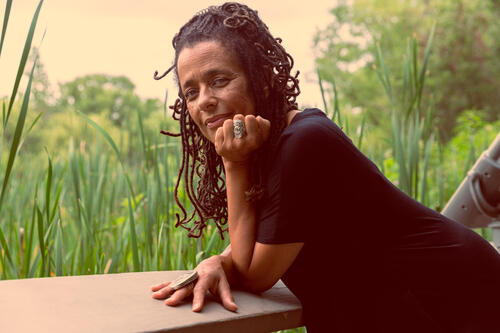 Carolyn Finney portrait on a railing outside