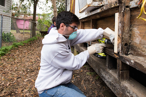 A student from Geneseo rips apart the siding from a destroyed home.